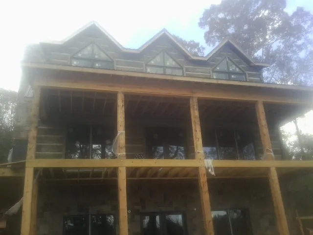 Dormers and porch framing on a large log home under construction — Roof Coating work by our crew in Waco